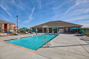 Airway Heights apartment for rent - A large swimming pool in front of a building with a blue sky above.