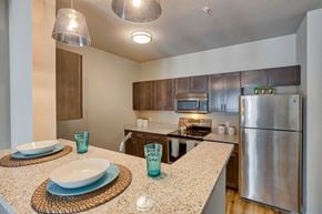 Airway Heights apartment for rent - A kitchen with a stainless steel refrigerator and a countertop with a white plate and blue glasses on it.