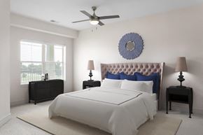 Olathe apartment for rent - A bedroom with a large bed, a ceiling fan, and two lamps.