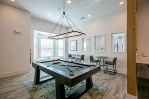 Olathe apartment for rent - A pool table is in the middle of a room with a light hanging from the ceiling.