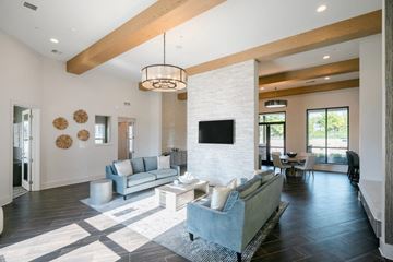 Olathe apartment for rent - A modern living room with a grey couch and a white brick wall.