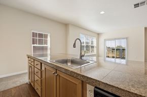 Gresham apartment for rent - Kitchen island with wooden cabinets overlooking living room with windows at Springwater Crossing apartments in Gresham, Oregon 97030