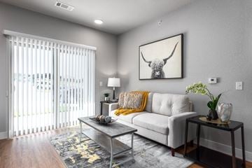 St. Peters apartment for rent - A living room with a white couch, a coffee table, and a painting of a bull's head on the wall.