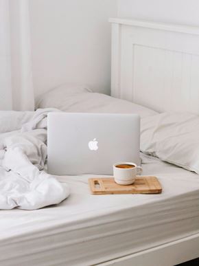 Irvine apartment for rent - A laptop with an Apple logo is on a bed with a cup of coffee.