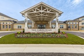 Wilson apartment for rent - The Carolinian building has a white entrance canopy and a flower bed in front.