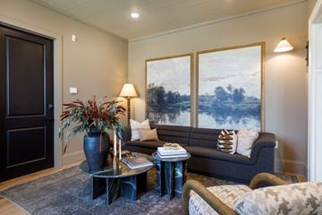 Wilson apartment for rent - A living room with a grey couch, a black door, and a painting on the wall.