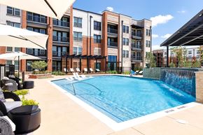 Celina apartment for rent - A pool surrounded by a patio with chairs and umbrellas.