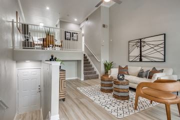 Plano apartment for rent - A living room with a white couch, a wooden chair, and a rug with a geometric pattern.