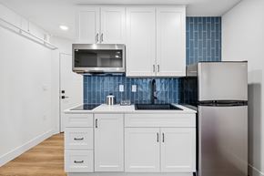 Boise apartment for rent - A kitchen with white cabinets and a blue tile backsplash.