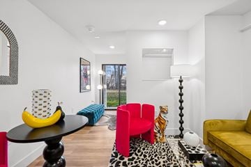 Boise apartment for rent - A living room with a yellow couch, a red chair, and a black table with a banana on it.