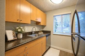 Aloha apartment for rent - A kitchen with wooden cabinets and a black countertop.