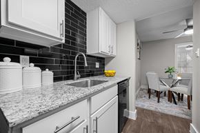 Dallas apartment for rent - A kitchen with white cabinets and a black tile backsplash.
