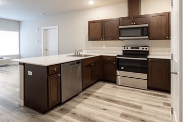 Medical Lake apartment for rent - A kitchen with dark wood cabinets and a white counter.