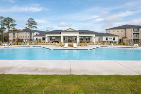 Shallotte apartment for rent - A large swimming pool in front of a building with a grassy area in the foreground.