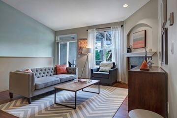 Tumwater apartment for rent - A grey couch with a red pillow sits in a living room.