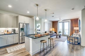 Lewisville apartment for rent - A modern kitchen with a bar area and a living room with a couch.