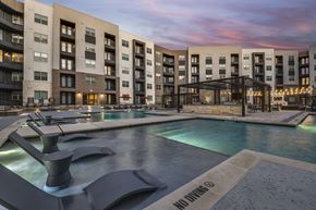 Lewisville apartment for rent - A modern building with a pool in front and a