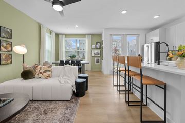 Charlotte apartment for rent - A modern living room with a white couch and a kitchen area in the background.