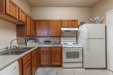 Houston apartment for rent - A kitchen with wooden cabinets and white appliances.