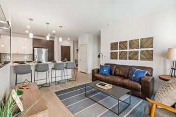 Denver apartment for rent - A modern living room with a brown couch and a dining table with four chairs.