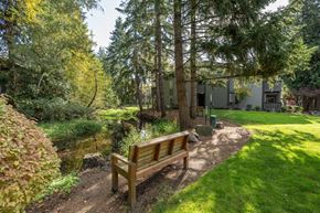 Kirkland apartment for rent - A wooden bench sits in a grassy area next to a pond.
