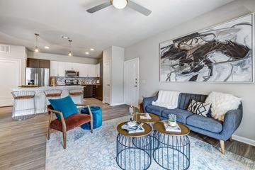 Pflugerville apartment for rent - A living room with a blue couch and a large painting on the wall.