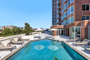 Dallas apartment for rent - A swimming pool with a white umbrella in the middle of it.