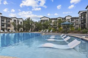 San Antonio apartment for rent - A swimming pool with lounge chairs and apartment buildings in the background.