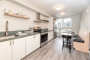 Oakland apartment for rent - a kitchen with white cabinets and a black table and chairs