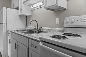 Spokane apartment for rent - A white stove top oven with a silver sink and a white refrigerator in a kitchen.