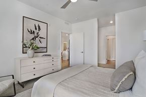 American Fork apartment for rent - Alvera at the Meadows bedroom with a large bed, a dresser with a vase of flowers, and a framed picture on the wall.