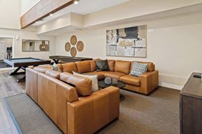 Salt Lake City apartment for rent - A brown leather couch with a blue pillow is in the center of a living room.