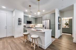 Mckinney apartment for rent - A kitchen with a white island and wooden bar stools.