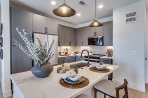 Lewisville apartment for rent - A modern kitchen with a marble countertop and a dining table set for two.