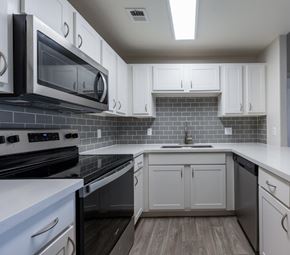 Phoenix apartment for rent - A kitchen with white cabinets and black appliances.