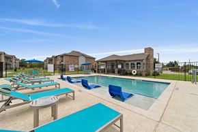 Gunter apartment for rent - A pool area with sun loungers and a building in the background.