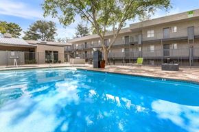 Tucson apartment for rent - A swimming pool in front of a building with a tree.