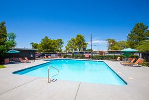Tucson apartment for rent - A large swimming pool with a diving board and lounge chairs.