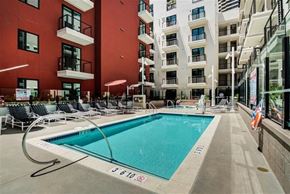 San Diego apartment for rent - A swimming pool in front of a red building with lounge chairs around it.