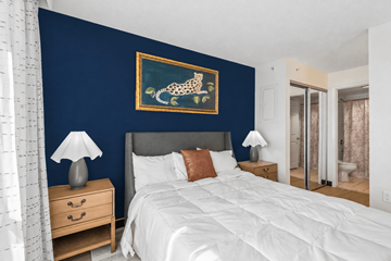 Houston apartment for rent - A bedroom with a large bed, a nightstand with a lamp, and a painting on the wall.