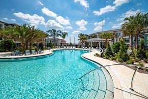 Winter Garden apartment for rent - A large swimming pool surrounded by palm trees and a building in the background.