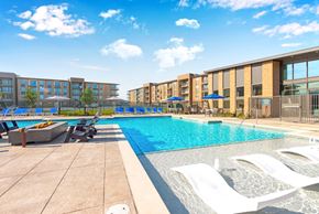 Grand Prairie apartment for rent - A swimming pool with sun loungers and apartment buildings in the background.