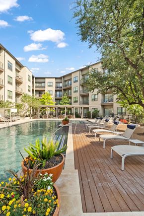 San Antonio apartment for rent - A pool area with chairs and a building in the background.