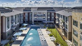 North Richland Hills apartment for rent - A swimming pool is surrounded by apartment buildings.
