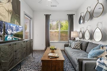 Garland apartment for rent - A living room with a grey couch, a wooden coffee table, and a large painting on the wall.