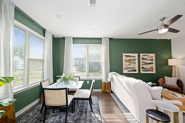 Charlotte apartment for rent - Axis at the Park model living room with a white couch, a dining table with chairs, and a ceiling fan.