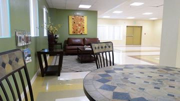San Diego apartment for rent - A living room with a brown leather couch, a checkered chair, and a round table with a mosaic design.