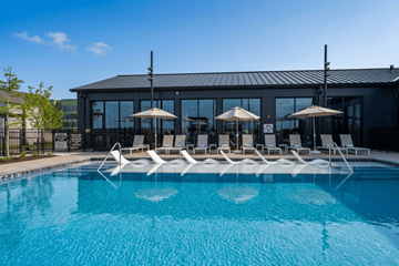 Allen apartment for rent - A pool with chairs and umbrellas in front of a building.