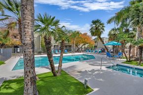 Tucson apartment for rent - A pool surrounded by palm trees and a fence.