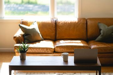 San Antonio apartment for rent - A brown leather couch with a laptop and a cup on a wooden table in front of it.